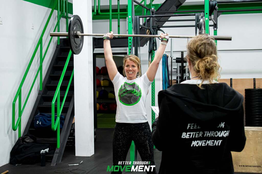 Vrouw lacht tijdens CrossFit training met barbell in fitness sportschool Zevenbergen